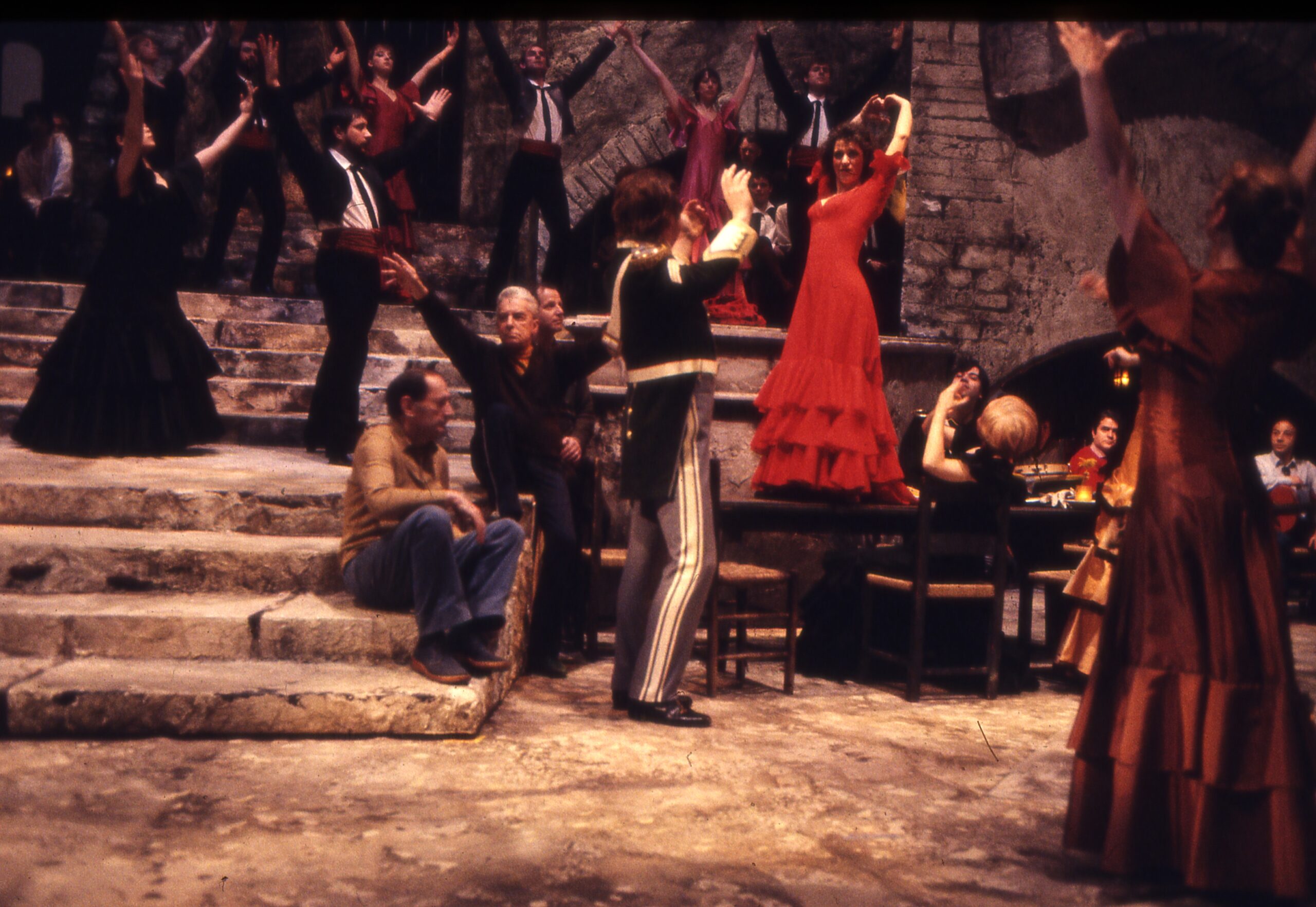 Herbert von Karajan seated on steps during a Carmen rehearsal, with Agnes Baltsa in a red dress.